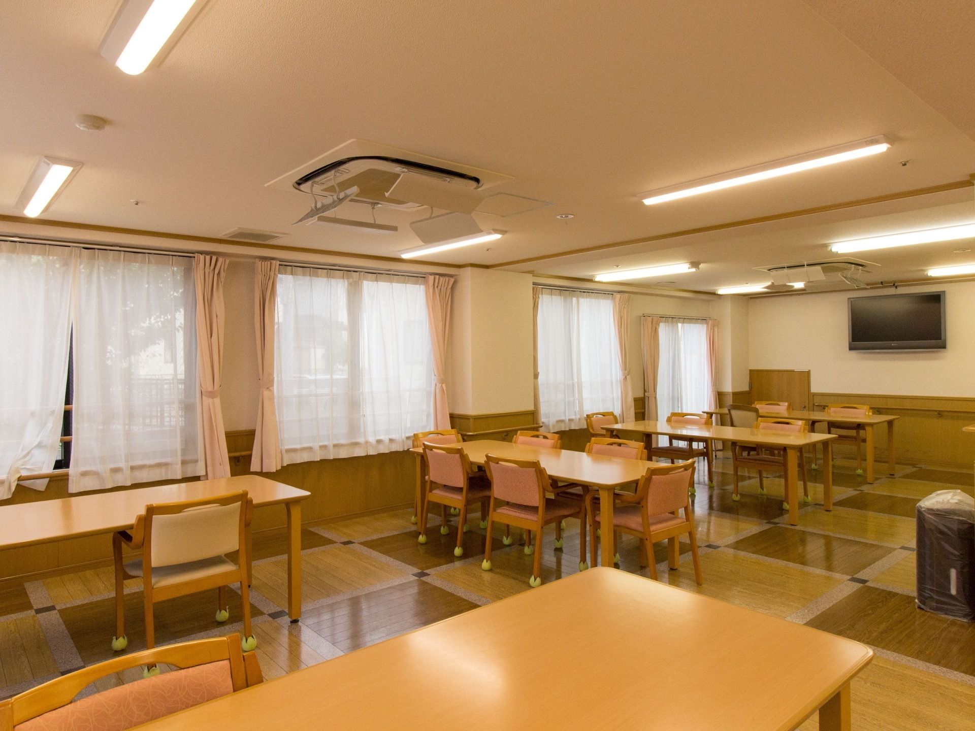 広いフロアに、間隔を十分に開けてテーブルを配置している。テーブルも大きめのものを使用している。大画面テレビも設置されている。