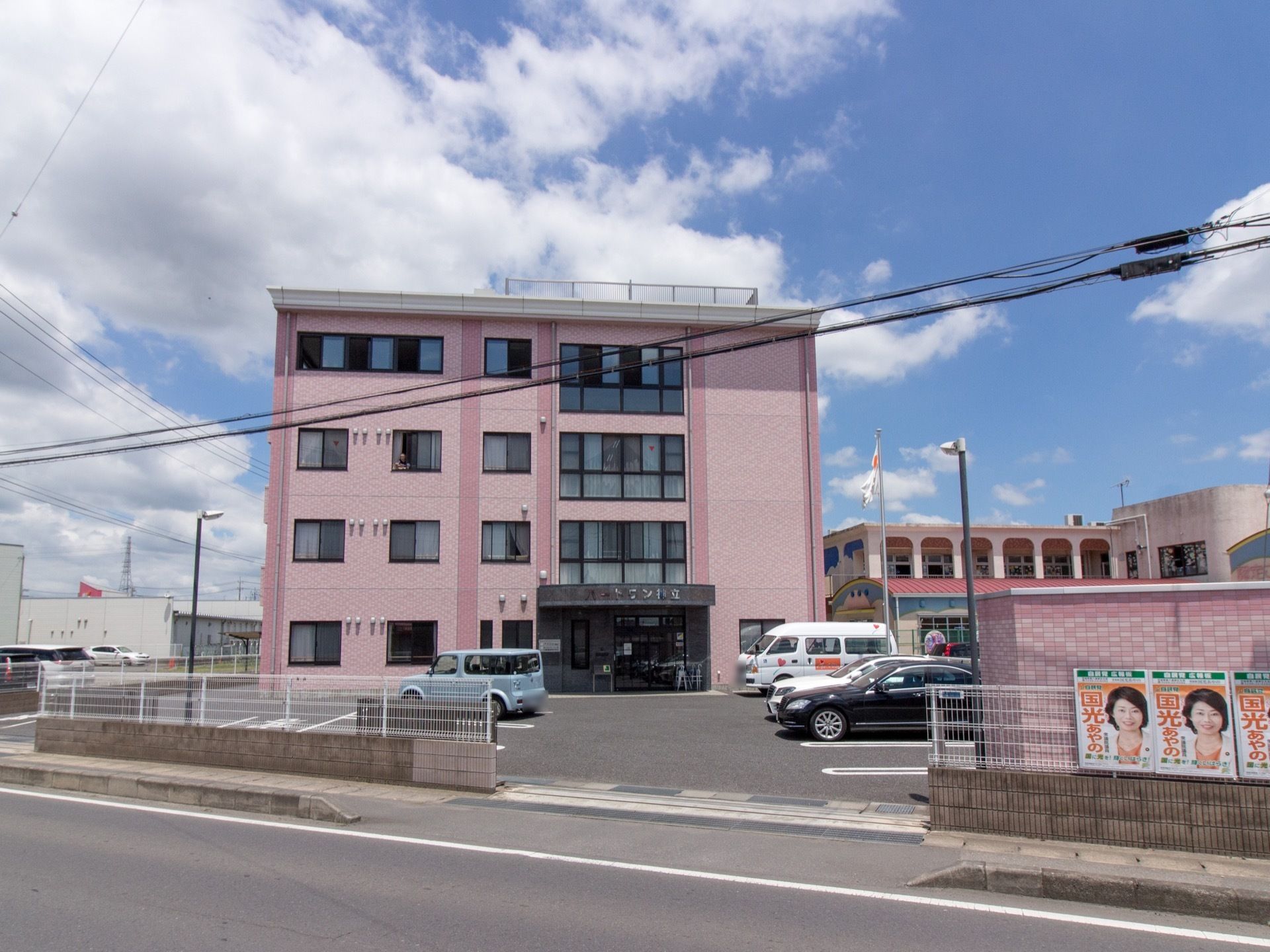 淡いピンク色の外観で優しい雰囲気となっている。屋上には柵が設置されており入居者様は自由に利用することができる。