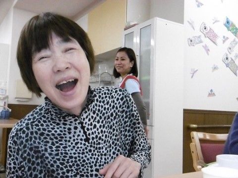 こいのぼりの掲示物が貼られた白い壁の前で、笑顔を見せる女性