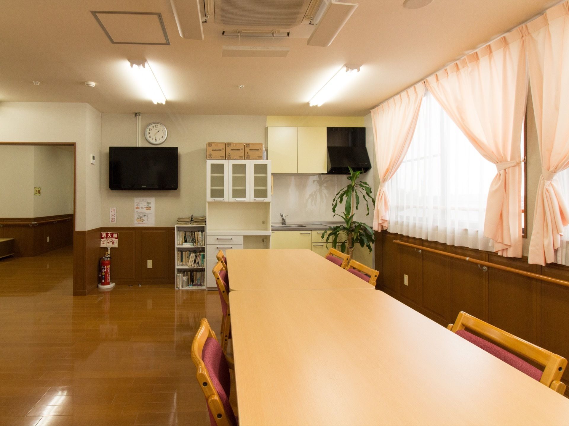 食堂には長テーブルが設置されている。壁側には手すりが設置されており、入居者様の着席と離席がスムーズに行えるようになっている。
