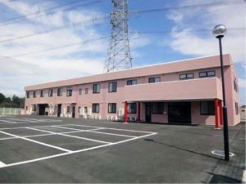 淡いピンクの2階建ての建物の前に広がっている駐車場