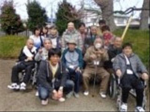 車椅子や椅子に座る高齢者を前列に、その後ろに立つ高齢者やスタッフ