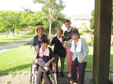 植木があり、歩道が整備された緑地の大きな柱の左にいる5人の人物