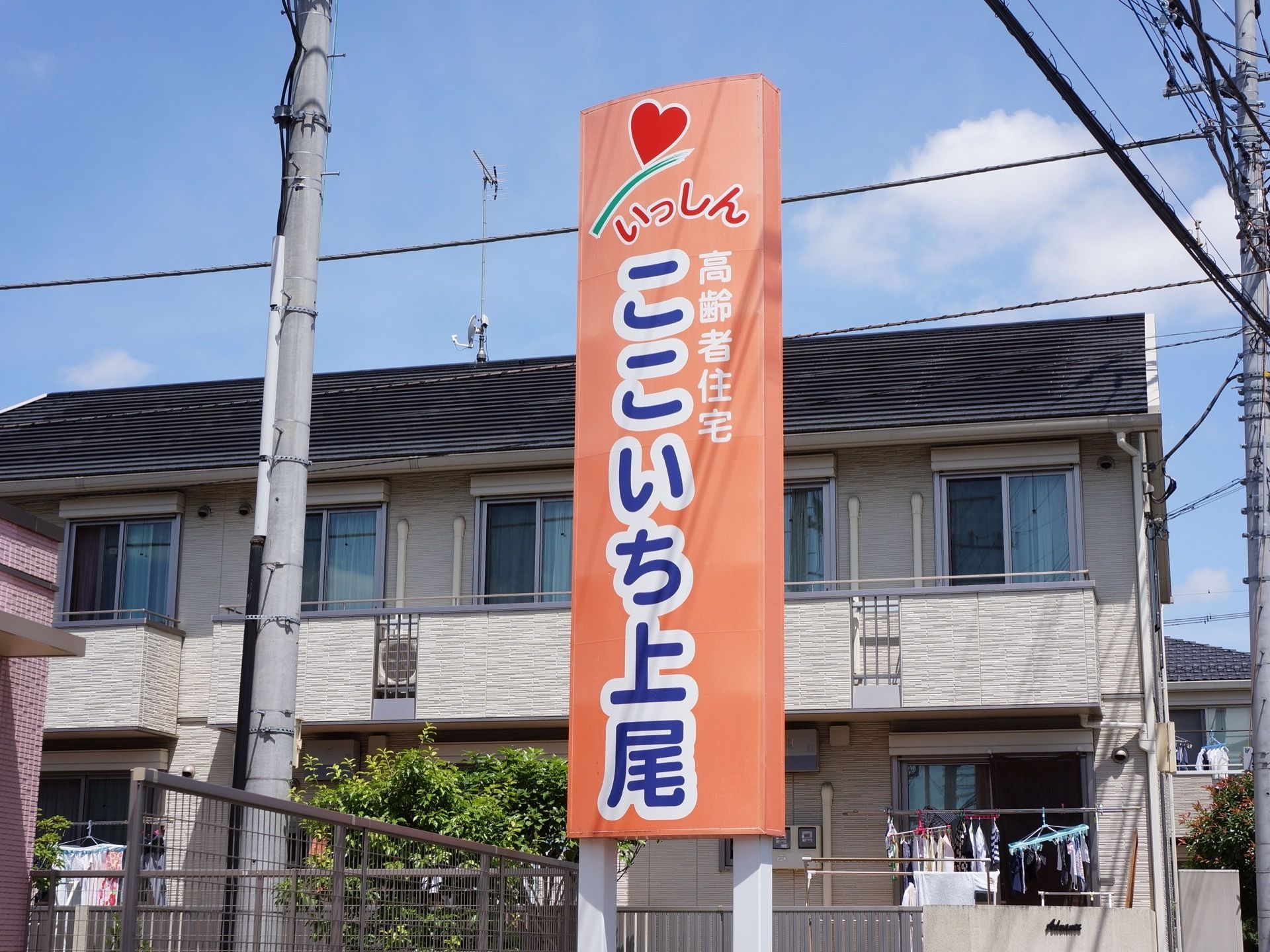 明るいオレンジの看板は白い縁取りのある青い文字で施設名が書かれており、遠目で見ても目立つ看板になっている。