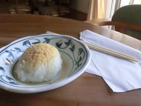 丸い柄付きのお皿にきな粉のかかったお餅のようなものが盛られ、箸が添えられているテーブル