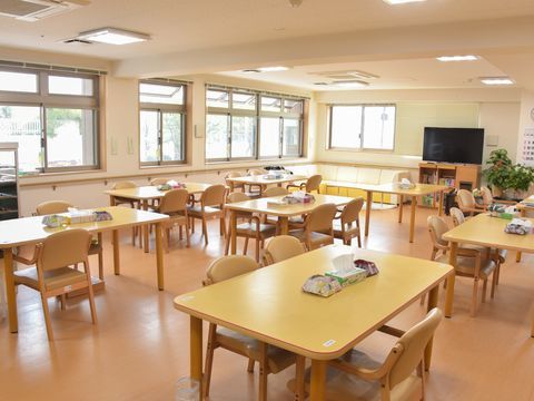 左と正面の2面に窓があり、右奥に大型テレビのある食堂