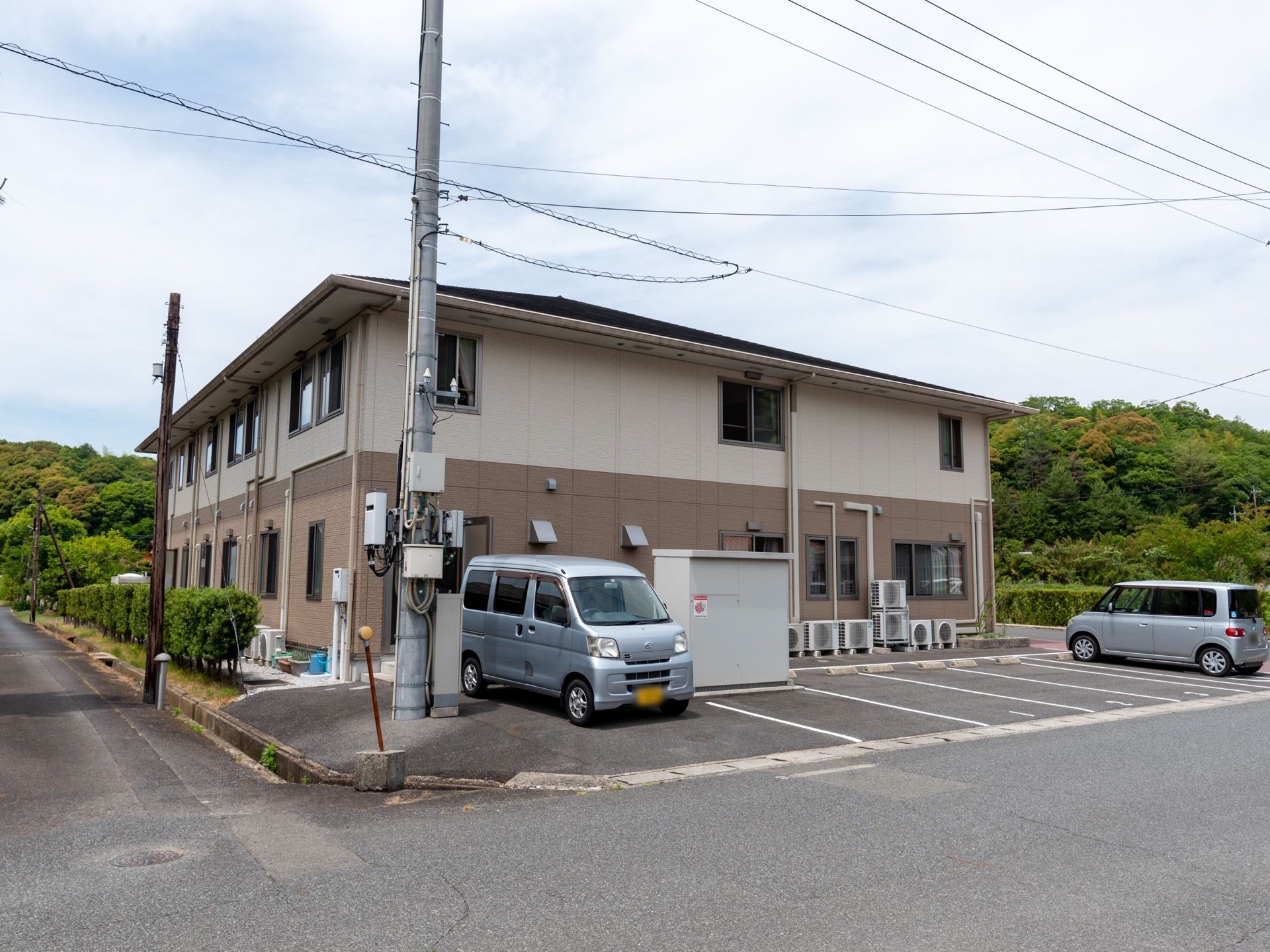 外観の施設は白とベージュのツートンカラーの外観で、２階建てである。敷地内に駐車スペースがある。建物の周囲には緑が多く、自然豊かである。