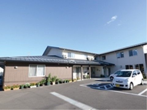 左は茶色の寄棟屋根の平屋、右は白い壁に黒い切妻屋根の2階建てが合わさった建物