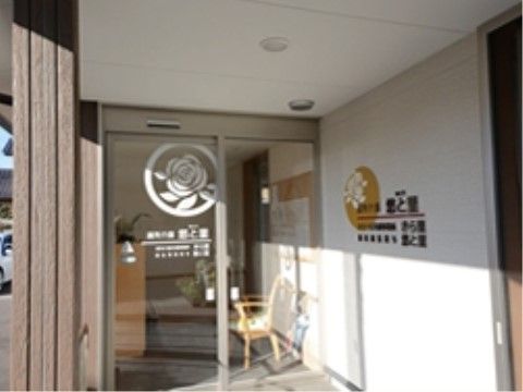 右の白い壁に施設名が入り、正面にガラスの自動ドアがある玄関