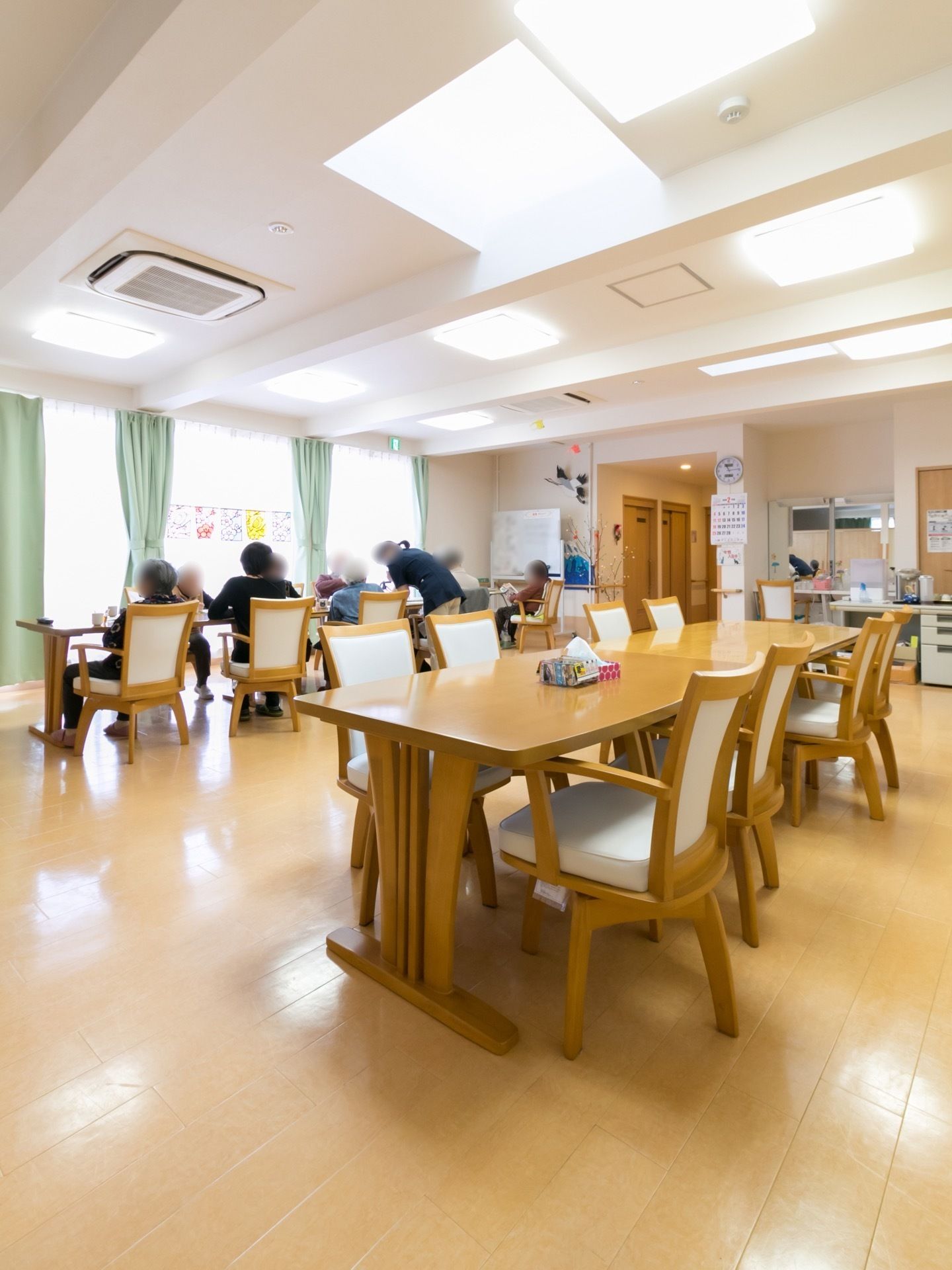 机と椅子が並べられている。柱に時計とカレンダーが掛けられている。事務机が１台置かれている。エアコンが完備されている。