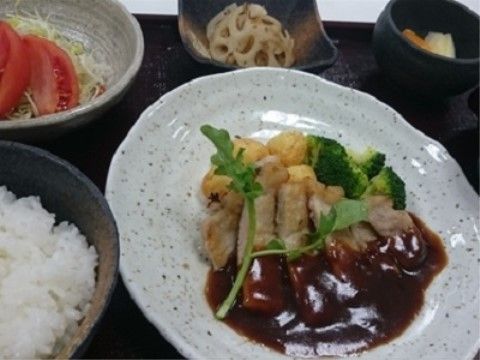 ソースのかかった豚ロースソテーとご飯、サラダなどがトレーに乗せられている。高齢の方も食べやすいように調理されている。