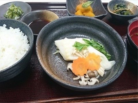 カレイの酒蒸し、ご飯、かぼちゃの煮物、きゅうりの酢の物などが盛り付けられている。食材の味を活かした味付けがされている。