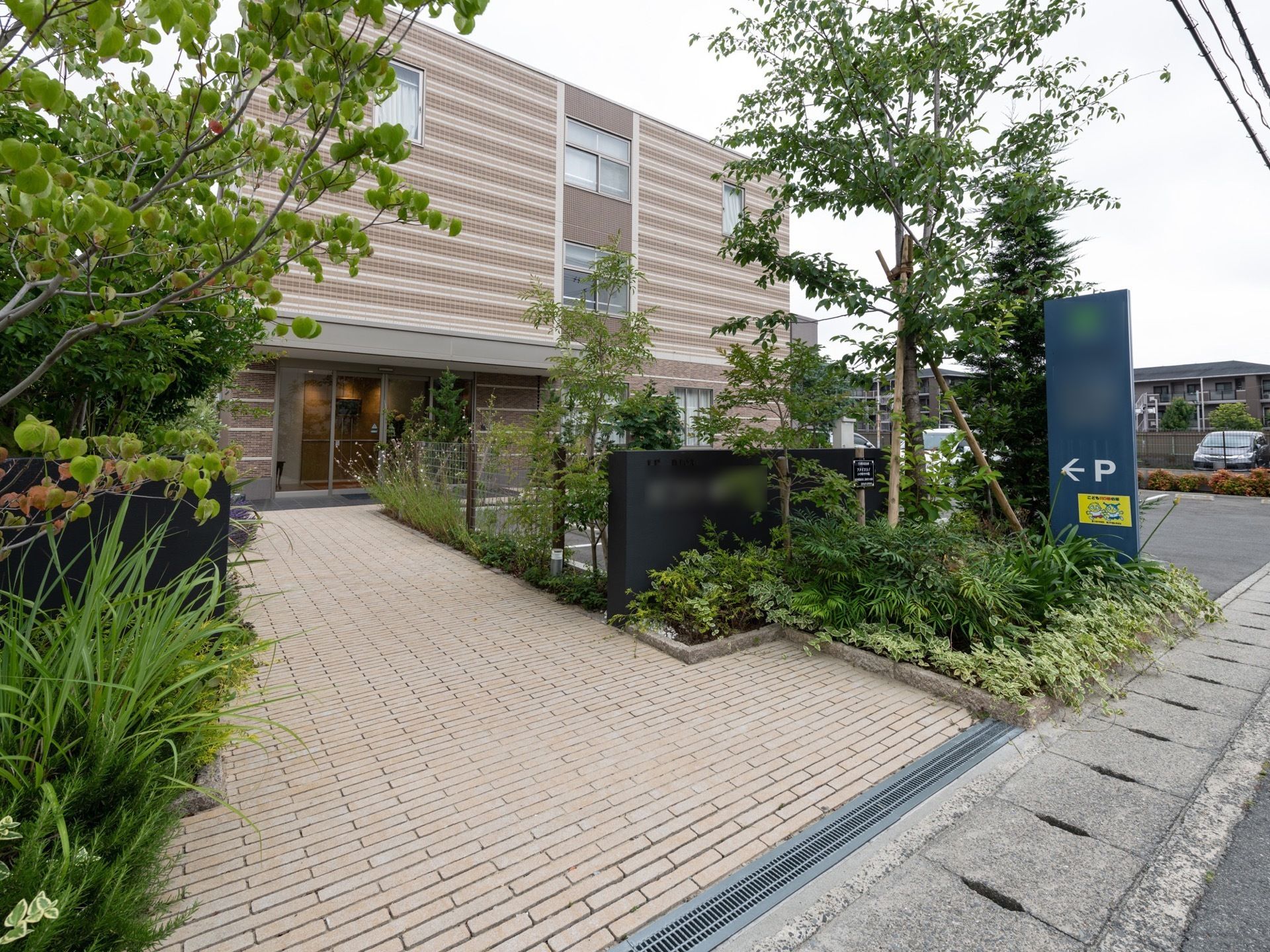 ブラウンの外壁と植栽のグリーンとのコントラストが美しい。建物の前にはゆったりとスペースが取られており、楽に行き来できる。
