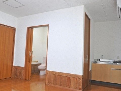 キッチンやトイレが備え付けられた広々とした居室である。清潔感のある白い壁紙が貼られており、下部は木目調となっている。