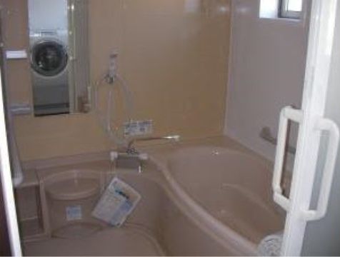 薄いオレンジとピンクの内装が、あたたかな雰囲気になっている。浴槽やカウンター部分は丸みを帯びたデザインになって入居者様のケガを防いでいる。