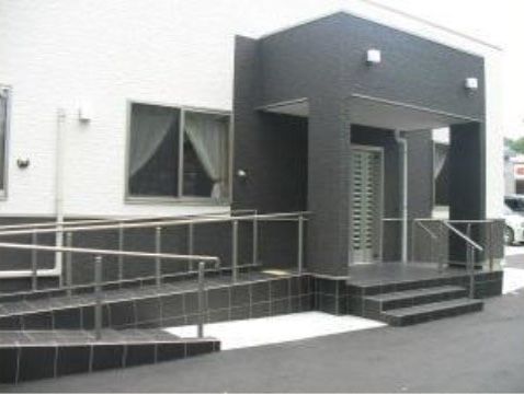 グレーとホワイトのモダンな外観。なだらかなスロープが設けられていて車椅子をご利用の方も安心して移動することができる。
