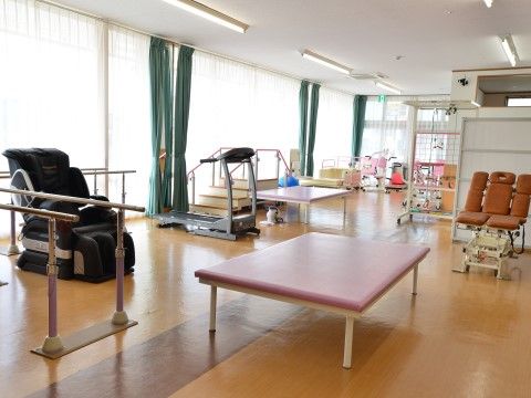 平行棒、ウォーキングマシンのほか、さまざまなトレーニング機器が設置されている。壁一面に設けられた窓から光が入り込んで明るい。