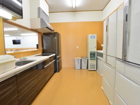 広いキッチンには、冷蔵庫、製氷機、流し台、電磁調理器が設置されている。収納スペースも十分に設けられ、室内は明るく整然としている。