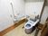 トイレの壁紙は花柄である。トイレットペーパーフォルダーが取り付けられている近くに2つの手すりがある。