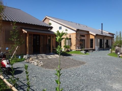 ライトブラウンに白のツートンカラーが特徴的な、瓦葺きの切妻屋根の平屋の建物