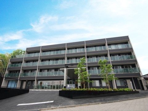 茶色い壁面に白いラインが縦に入ったデザインの4階建ての建物