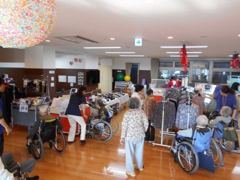 白い布のかかったテーブルに品物を並べたり、ハンガーに洋服をかけたりして展示されている共用スペース