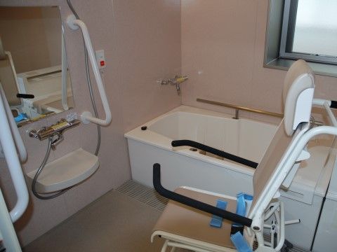 浴室には介助用の椅子が設置されている。黒色のクッションが付いた肘掛けがあり、入居者様は安全に座ることができる。