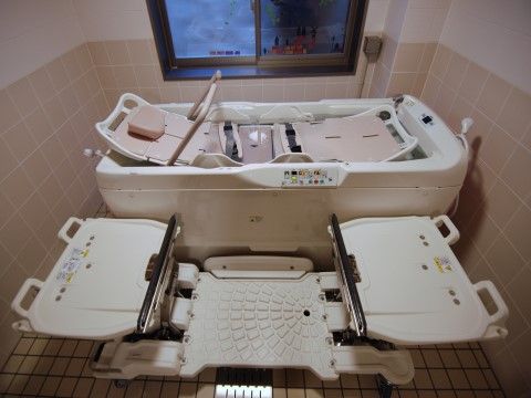 介護浴槽が設置されており、淡いピンク色を基調とした浴室である。入居者様の状況に応じて器具を使い分けることが可能である。