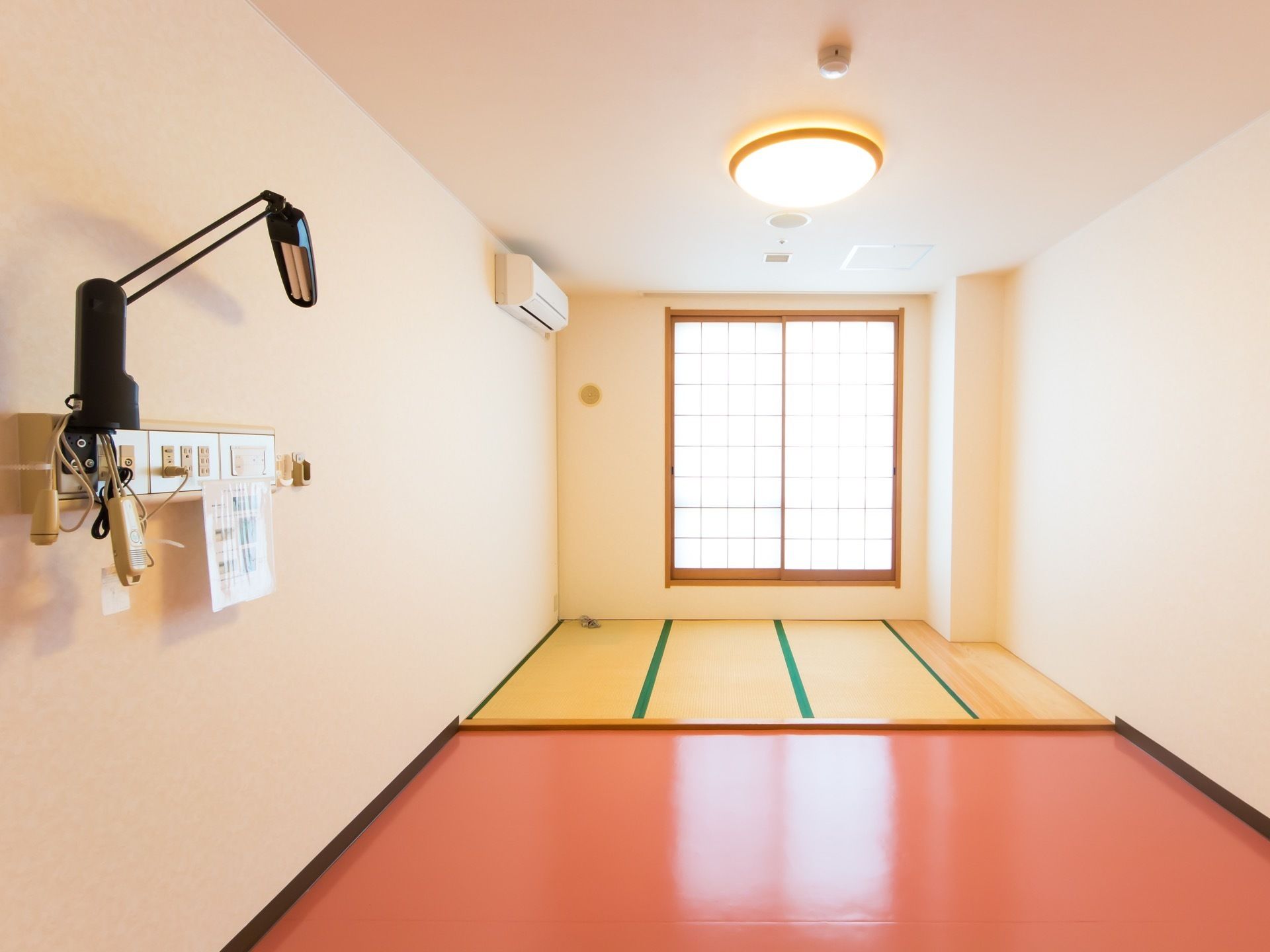 壁にエアコンが設置されたご入居前の和室タイプの居室である。障子窓や畳敷きのスペースが設けられている。
