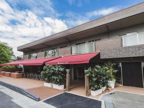 観葉植物が飾られ建物前に赤い屋根が設けれた高齢者施設の外観