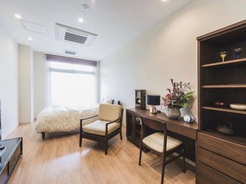 ベッドや棚、テーブルセットが配置されたエアコン付きの居室