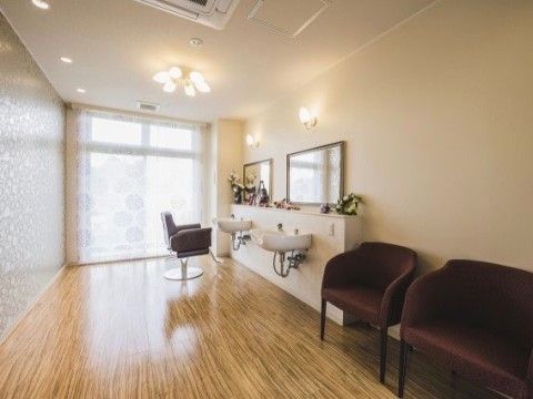 ゆったりとした空間に洗面台があり、奥には理容椅子が設置されている。手前にはダークブラウンの椅子が準備されている。