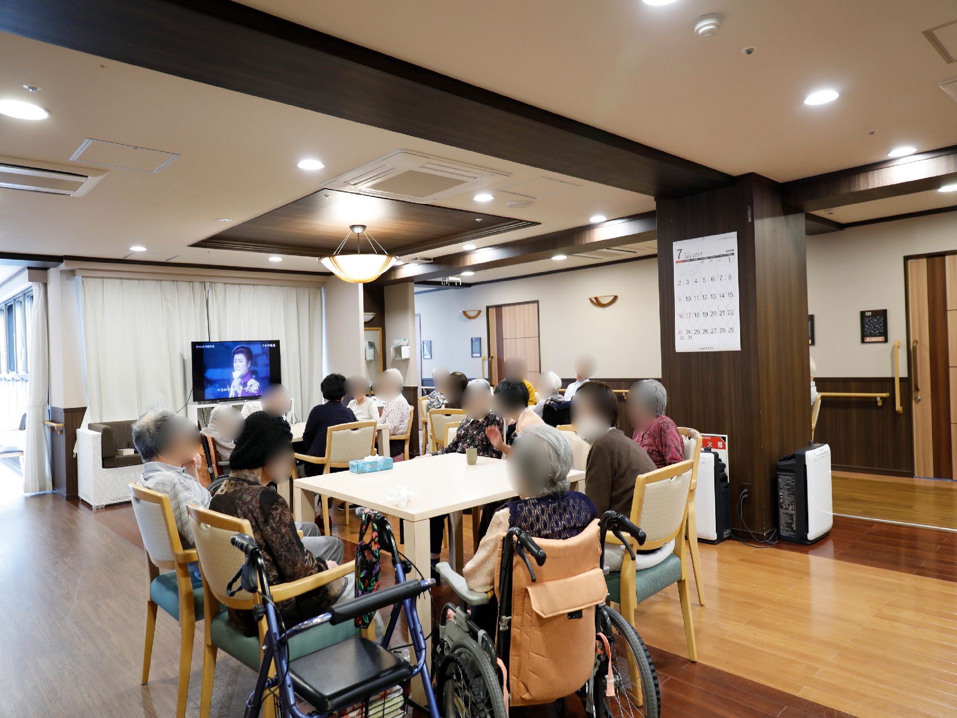 テレビが置かれている。テーブルや椅子がある。車椅子の人も安全に利用できるスペースとなっている。フラットな床である。