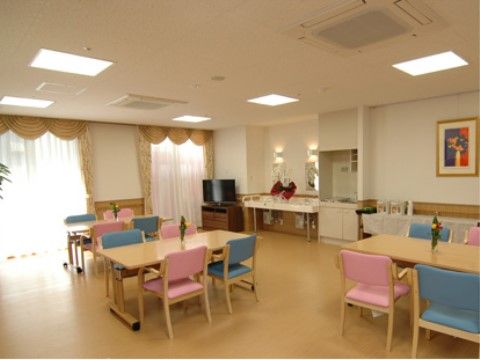 ピンク色と青色の椅子が交互に置かれていて、多くの照明がある食堂