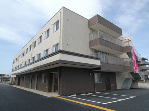 2台分の駐車場が隣接している、３階建ての白と茶色の建物