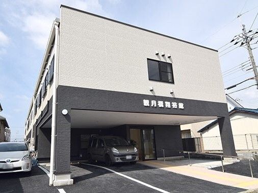 1階部分が黒色、2階がベージュの建物で、壁には施設名の切り文字看板