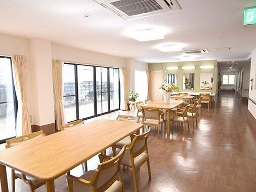 大きな窓から自然光の入るテーブルセットが配置された共有スペース