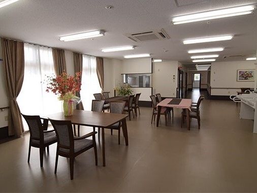 薬を飲む高齢女性に水を差し出す女性スタッフ
