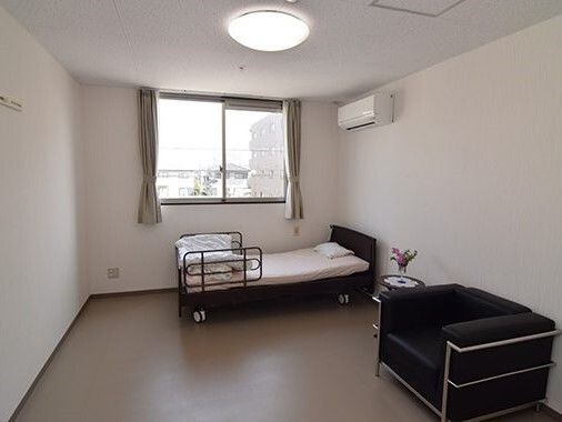 温かい色調の居室の中、ベッドとタンスの間に置かれた車椅子