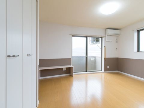 奥に窓がありその左にベンチ、右の壁面上部にエアコンがあるスペース