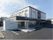 建物は３階建てで、玄関には屋根が設置されている。入口にはスロープがつながっており、駐車場も設けられている。
