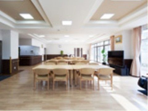床には木製のテーブル、手すり付きの椅子、大型テレビが設置されている。壁には大きな窓が設けられている。