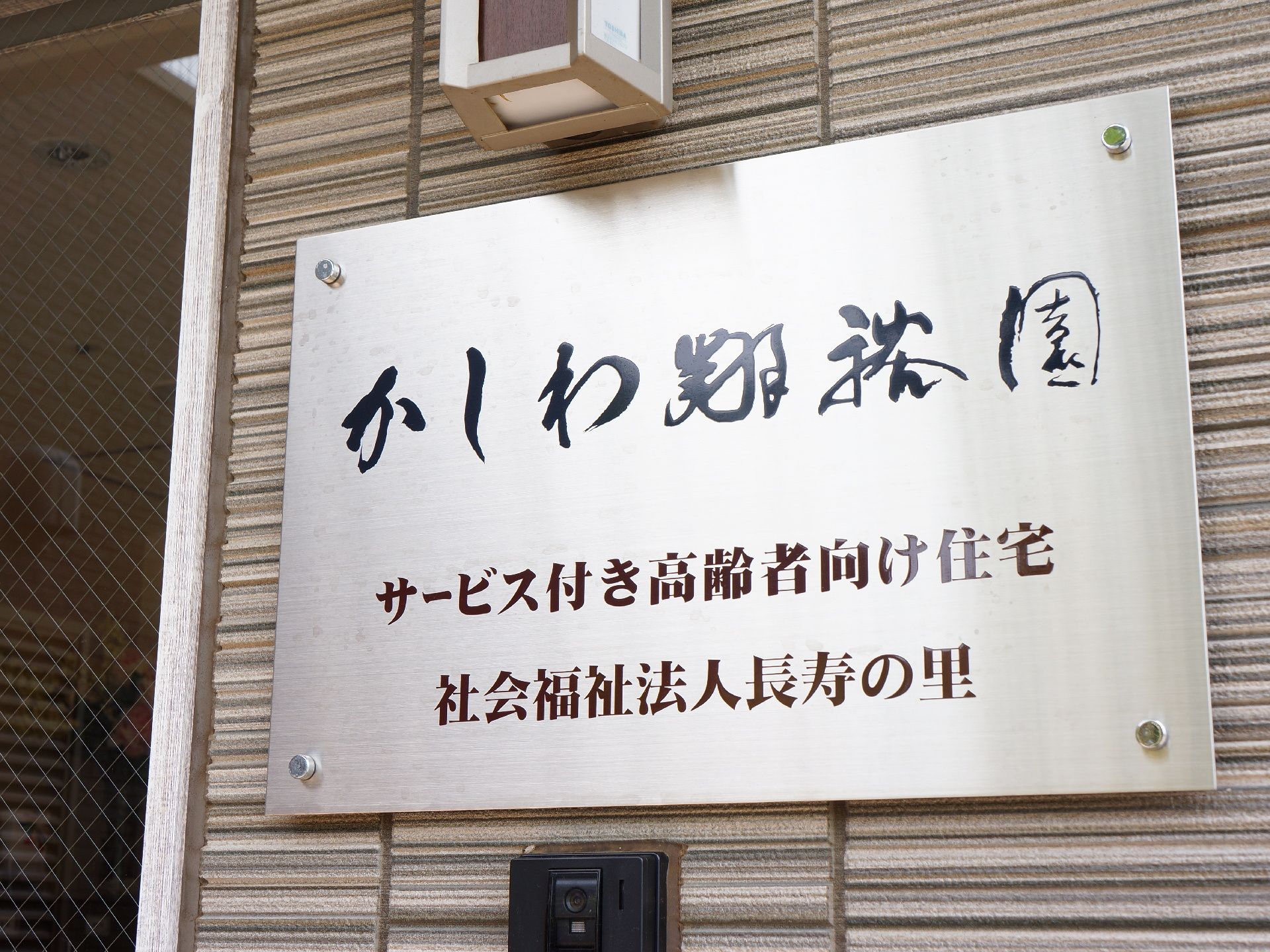 玄関脇に設置してある、サービス付き高齢者向け住宅「かしわ翔裕園」の看板。モダンな行書体で書かれている。