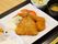 黒い長方形のプレートに1人分の食事がセットされている。白い角皿に3種類のフライが盛られ、複数の野菜が添えられている。