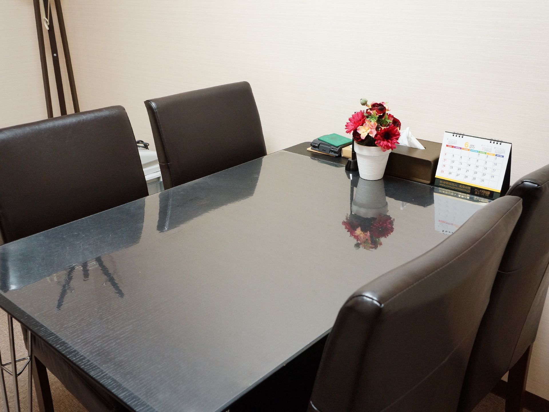 黒を基調とした４人掛けテーブルと椅子が用意されている。テーブルにはカレンダーと花が添えられており、落ち着いた雰囲気を作っている。