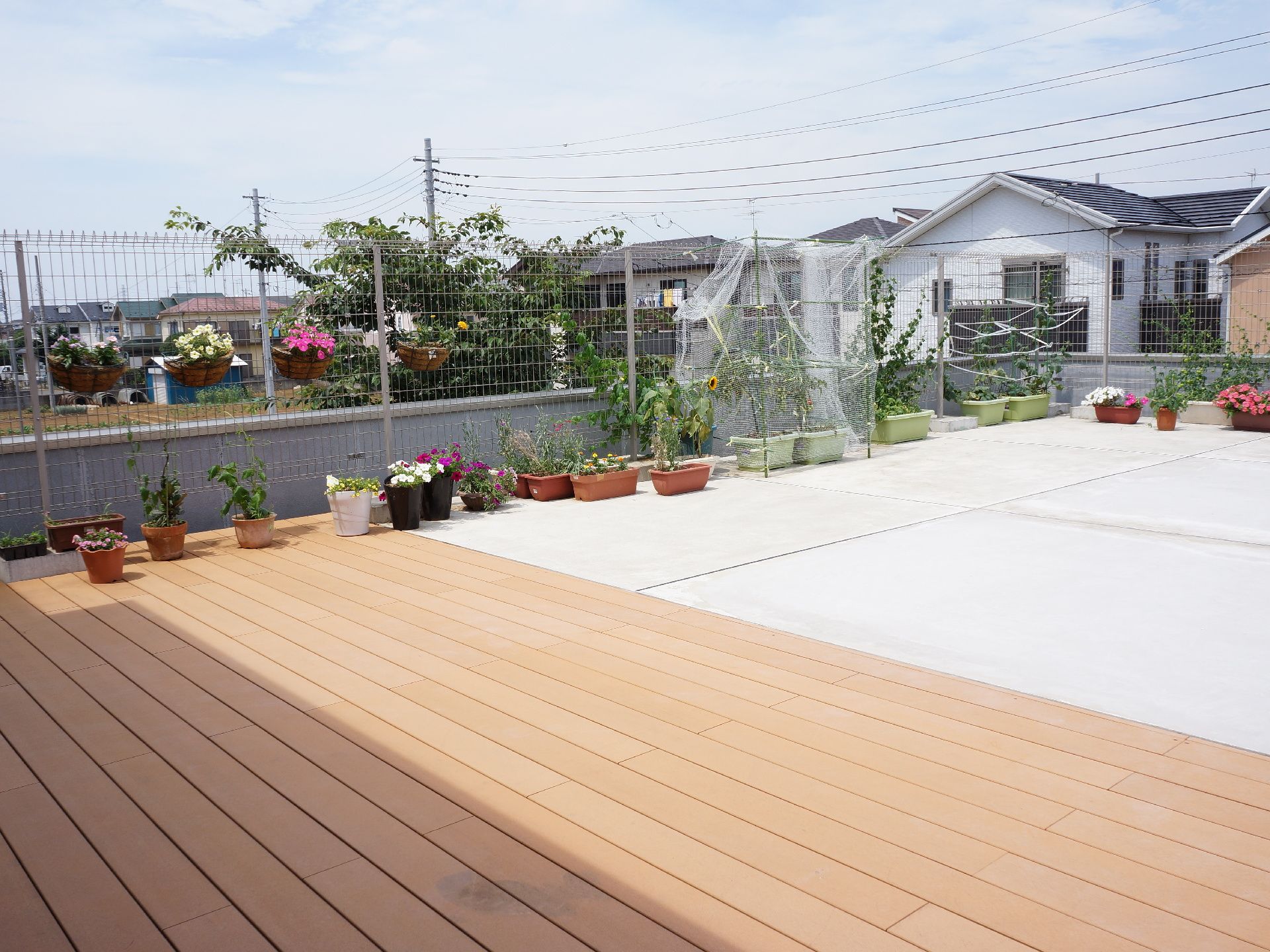 コンクリートとウッド調のバルコニーは広く、沢山のプランターで花や緑を育てている。バルコニーからは空を一望することができる。