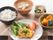 白米をはじめ、主菜はソースがかかった焼鮭、副菜に南瓜の煮つけと青菜のおひたし、汁物に味噌汁と一般的な和風の彩りのいい食事が並んでいる。