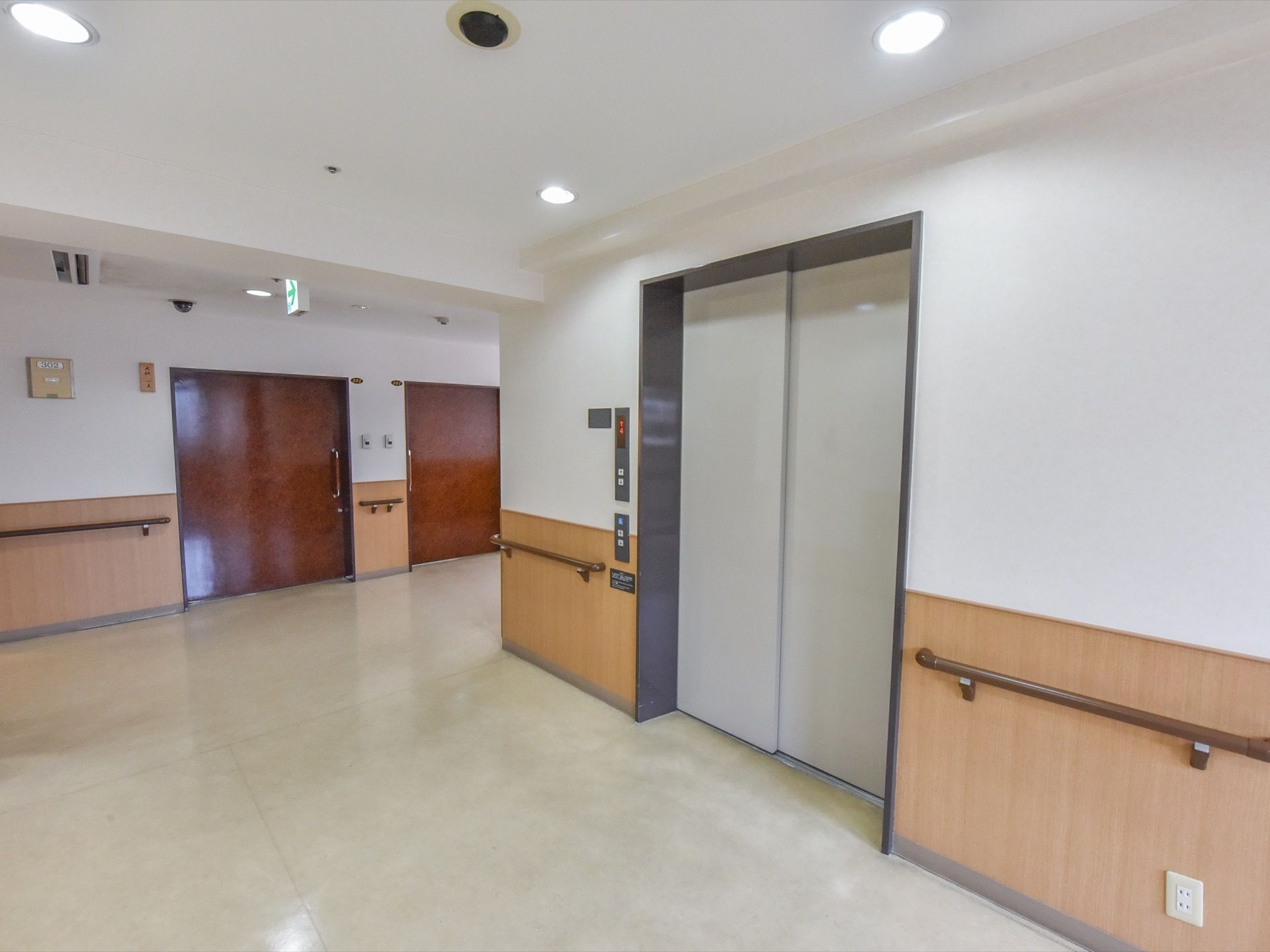 扉が閉まっている状態のエレベーターがあり、横には階数表示板、下の方には車椅子の人専用のボタンがある。