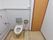 トイレには、蓋のないタイプの便座がある。両サイドには手すりがあり、壁際にはナースコールが設置されている。