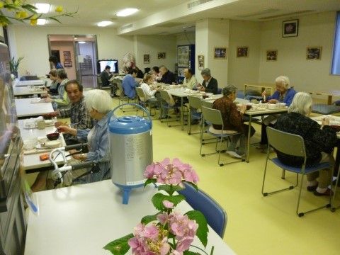 白い壁、黄緑の床に白いテーブルが2列に並べられた食堂